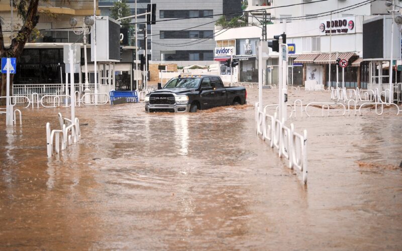 A car drives in a flooded road in the northern Israeli city of Nahariyya