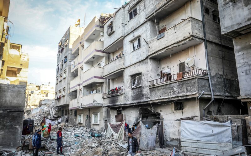 Palestinians stand in front of their destroyed homes